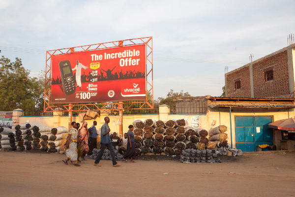 Charcoal traders photographed beneath a mobile phone poster in Juba South Sudanjpg