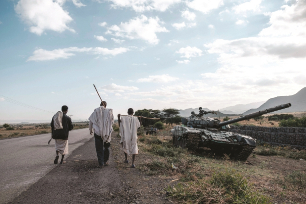 People walk next to an abandoned tank belonging to Tigrayan forces south of the town of Mehoni Ethiopiajpg