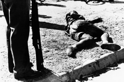 A policeman stands over the corpse of a South African killed by police during a demonstration at Sharpeville in 1960. 