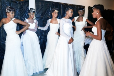 Models in traditional white gowns at a Kinshasa fashion show.